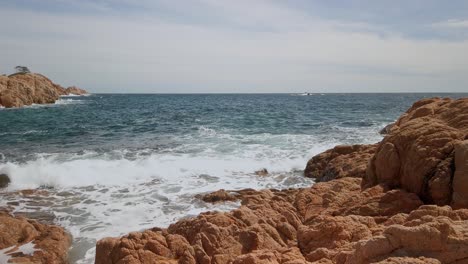 Olas-Panorámicas-Del-Océano-Rompiendo-En-El-Fondo-Del-Horizonte-Del-Acantilado-Rocoso-Terroso-Mediterráneo-En-La-Costa-Brava-Es-Una-Región-Costera-De-Cataluña