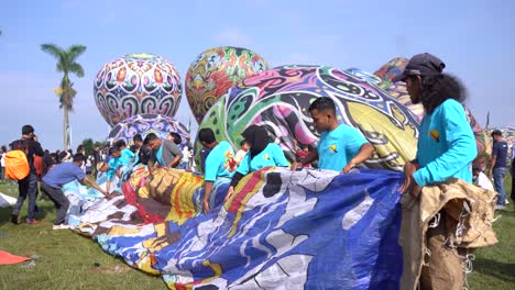 Participants-roll-up-a-hot-air-balloon-that-has-finished-flying-as-part-of-the-hot-air-balloon-festival-in-the-twin-village,-Wonosobo