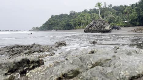 Eine-Aufnahme-Aus-Niedriger-Perspektive-Von-Wellen,-Die-Auf-Kleine-Felsen-Am-Abgelegenen-Strand-Playa-Terco-In-Der-Nähe-Von-Nuquí-Im-Departement-Chocó-An-Der-Pazifikküste-Kolumbiens-Schwappen