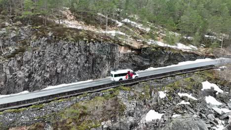 Tourists-exit-white-minibus-to-watch-a-waterfall-in-early-spring-season-with-snow-still-around