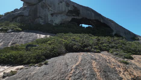 Aerial-approaching-shot-of-Frenchman-Mountain-in-Cape-Le-Grand-Area-with-green-bush-and-cave-at-sunny-day