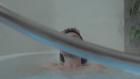 Slow-motion-rising-shot-of-an-attractive-man-relaxing-in-a-spa-bath