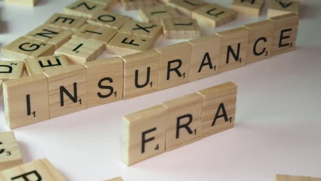 Narrow-focus-close-up-Scrabble-letters-make-words-INSURANCE-and-FRAUD