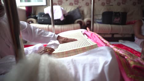 A-Sikh-elder-is-engrossed-in-reading-the-sacred-scripture-within-the-confines-of-his-temple,-depicted-from-a-close-up-perspective