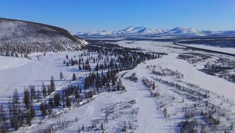 frozen-river-against-the-backdrop-of-mountains-and-trees-in-Yakutia-from-a-4k-drone