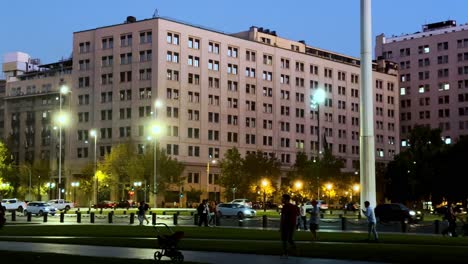 Schwenk-Folgt-Fußgängern,-Die-In-Der-Abenddämmerung-Vor-Dem-Präsidentenpalast,-La-Moneda,-Santiago,-Chile-Flanieren