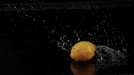 Eine-Zitrone-Taucht-Ins-Wasser-Ein,-Dreht-Sich-Und-Verursacht-Spritzer-Vor-Einem-Schwarzen-Hintergrund