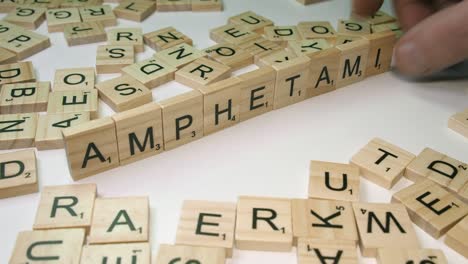 Scrabble-tile-letters-on-white-table-top-form-word-AMPHETAMINE,-game