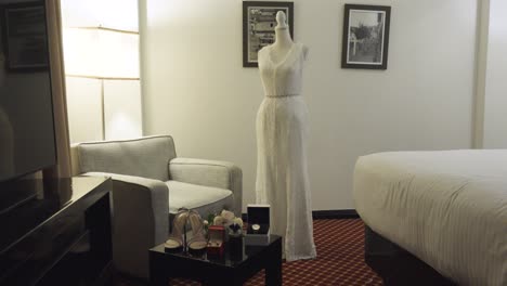 A-white-wedding-dress-is-displayed-on-a-mannequin-in-a-hotel-room