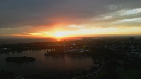 Vista-Aérea-Por-Drones-De-Una-Puesta-De-Sol-Cambiante-En-El-Parque-Y-El-Lago-Albert,-Melbourne,-Australia