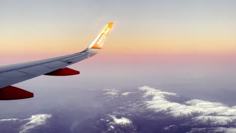 EasyJet-Flugzeug-Fliegt-Bei-Sonnenaufgang-über-Die-Alpen-Mit-Leuchtendem-Himmel