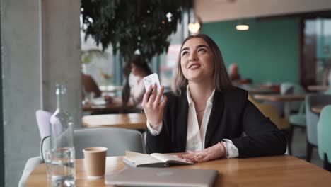 Hermosa-Mujer-En-Un-Café,-Vestida-De-Negocios,-Recibe-Un-Mensaje-Alegre-Sobre-Ganar,-Dinero-Y-Victoria.