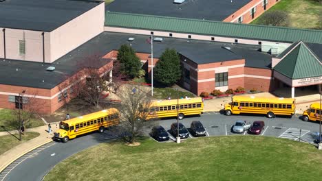 Vista-Aérea-Que-Muestra-A-Los-Niños-Saliendo-De-La-Escuela-Y-Corriendo-Hacia-El-Autobús-Escolar-Amarillo