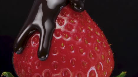 The-rich-chocolate-liquid-is-poured-down-the-succulent-strawberries-fruit,-set-against-a-black-backdrop,-embodying-the-concept-of-delectable-fruit-desserts