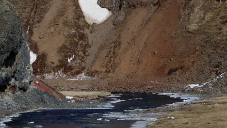 A-river-winding-through-mountains-in-early-Spring