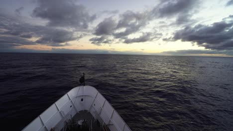 POV-Desde-La-Proa-Del-Barco-Mientras-Navega-Constantemente-Hacia-El-Horizonte-Del-Atardecer-En-Mar-Abierto