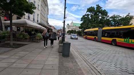 Strolling-through-the-streets-of-Warsaw,-Poland,-amidst-pedestrian-areas-adjacent-to-bustling-bus-and-car-traffic,-embodying-the-spirit-of-travel-and-exploration