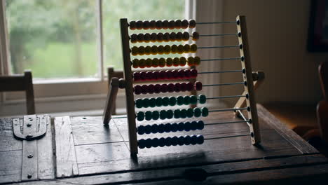 Multicolored-abacus-standing-on-a-weathered-wood-table,-with-a-backdrop-of-natural-light-and-greenery
