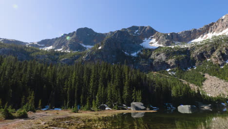 Handheld-panning-shot-of-high-mountain-peaks-and-a-marshy-alpine-lake