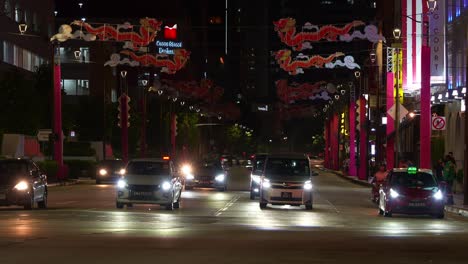 Night-scene-capturing-vehicle-traffic-on-Upper-cross-street-in-Chinatown,-street-decorated-with-dragon-themed-props-for-Chinese-lunar-new-year,-static-shot