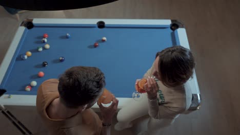 Slow-motion-establishing-shot-of-a-couple-drinking-beside-a-pool-table