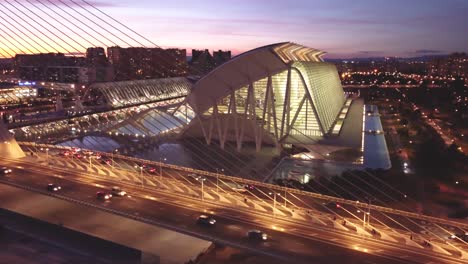 Abendsonnenuntergang-Und-Lichter-Der-Stadt-über-Valencia,-Spaniens-„Stadt-Der-Künste-Und-Wissenschaften“:-Ein-Filmreifer-Anblick,-Verkehr-Fährt-Zur-Goldenen-Stunde-über-Die-Brücke