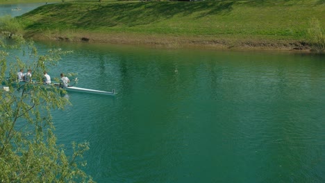 Ein-Team-Von-Vier-Männern-Rudert-In-Einem-Boot-Auf-Dem-Türkisfarbenen-Wasser-Des-Jarun-Sees-In-Zagreb,-Kroatien