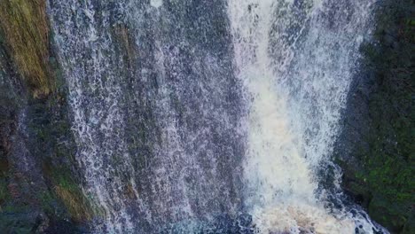 Aerial-drone-footage-of-a-tall-rocky-waterfall-in-the-Yorkshire-Dales,-Pennies