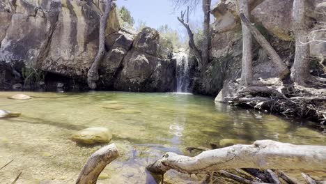 Una-Hermosa-Cascada-Rodeada-De-árboles,-Ramas-Y-Rocas