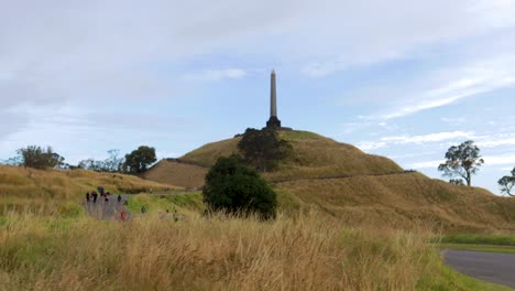 City-monument-at-Auckland-outskirts,-green-fields-of-cornwall-park-with-kids-playing