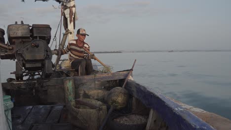 Un-Pescador-Tradicional-De-La-Aldea-De-Muncar-Dirige-Su-Barco-Y-Vierte-Redes-De-Pesca-En-El-Océano,-Mientras-Las-Gaviotas-Se-Deslizan-Por-Encima.