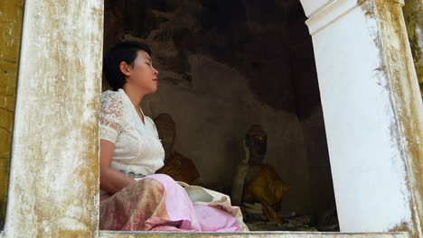 Mujer-Bonita-Tailandesa-De-Pelo-Corto-Meditando-En-Un-Templo-De-Cueva-Budista