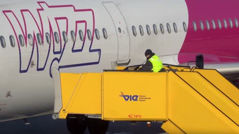 Man-controlling-boarding-stairs-connecting-to-WizzAir-Airbus-aircraft-at-Vienna-International-Airport