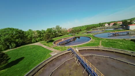 FPV-drone-low-flight-above-an-industrial-water-treatment-plant-with-water-containers-on-a-sunny-day