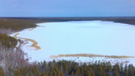 A-drone-rises-above-frozen-lakes-and-green-trees-4k