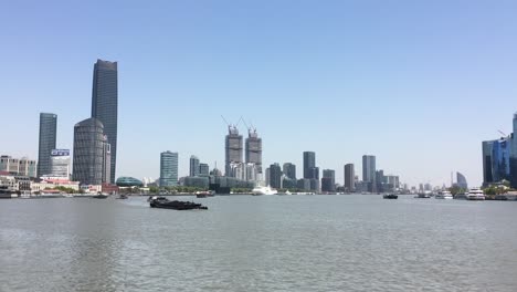Schiffe-Transportieren-Güter-Und-Material-Auf-Dem-Huangpu-Fluss-In-Pudong,-Shanghai,-Wolkenkratzer-Im-Hintergrund