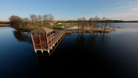 FPV-drone-shot-flying-over-a-pier-and-people,-spring-sunset-in-Masuria,-Poland