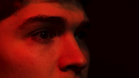 Young-man-reacts-with-a-shocked-face-in-close-up-while-light-up-by-red-light