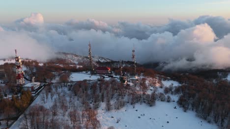 TV-masts-and-radio-station-on-snowy-mountain-above-cloud-inversion