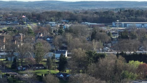 Drone-wide-shot-of-houses,-traffic-on-road-and-leafless-trees-during-spring-season-in-USA