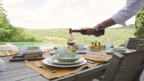 Mano-De-Camarero-Masculino-Apuntando-Rojo-Blanco-Sobre-Un-Vaso-Con-Piscina-En-El-Fondo