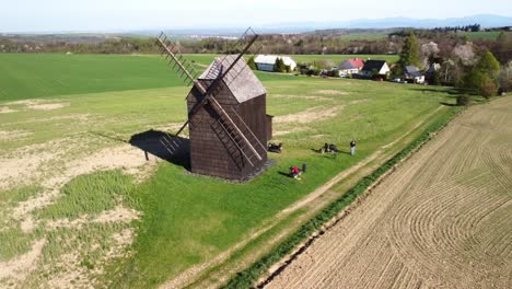 Nové-Dvory,-Bilovec,-Nový-Jičín-District,-Czech-Republic---People-Appreciating-the-Classic-Windmill-Set-in-a-Countryside-Scenery---Aerial-Pullback-Shot