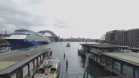 Sydney-Harbour-Terminal-and-Ferry-leaving-the-Wharf-and-Giant-Cruise-Ship-parked-at-the-passenger-terminal