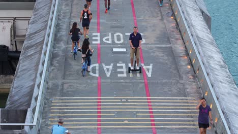 Singaporean-healthy-lifestyle,-people-riding-bike,-jogging,-strolling-across-the-reservoir-at-Marina-Barrage,-water-management-facility-in-Singapore,-irrigation,-flood-control-and-water-supply