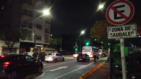 Blumenladen-Und-Pedidos-Ya-Fahrradlieferung-Nachts-In-Buenos-Aires,-Städtisches-Szenario,-Bus,-öffentlicher-Nahverkehr-Und-Verkehrszeichen-Im-Lateinamerikanischen-Großstadtgebiet