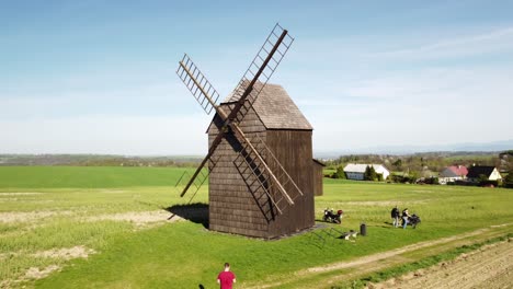 Nové-Dvory,-Bilovec,-Nový-Jičín-District,-Czech-Republic---Travelers-Exploring-the-Antique-Windmill-Amidst-the-Rural-Scenery---Aerial-Pullback-Shot