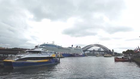 Sydney-Ferry-and-Giant-Cruise-Ship-parked-at-Sydney-Harbour-on-a-cloudy-day-at-Circular-Quay