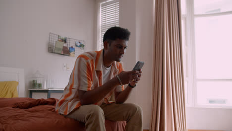 Indian-man-sitting-on-bed-with-phone