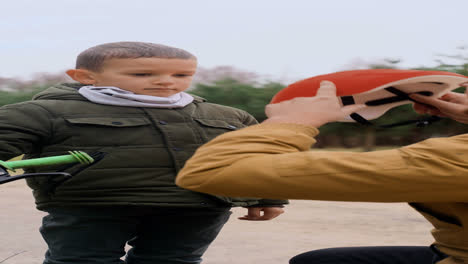 Papá-Poniéndole-Casco-De-Bicicleta-A-Su-Hijo