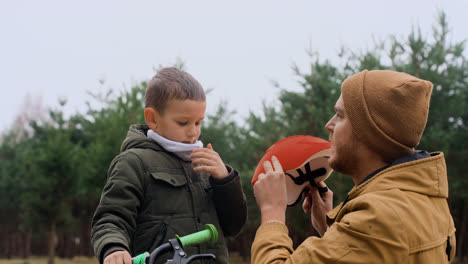 Papá-Poniéndole-Casco-De-Bicicleta-A-Su-Hijo